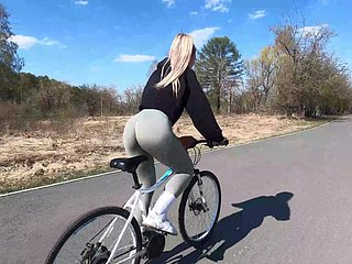 Ciclista bionda mostra il suo amico pesca al suo right-hand man e scopa nel parco pubblico